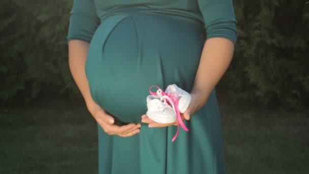 Femme enceinte avec des chaussures blanches enfant dans les mains — Video