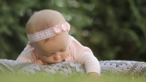Babymeisje liggend op de plaid in het park van de zomer — Stockvideo