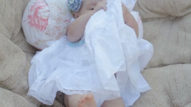 Babymeisje zit in witte jurk in stoel — Stockvideo