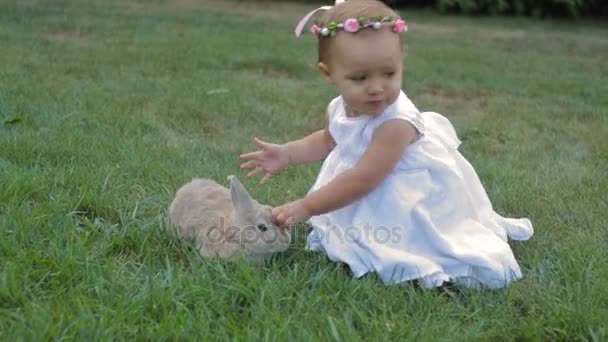 Kleines Mädchen im weißen Kleid streichelt das Kaninchen