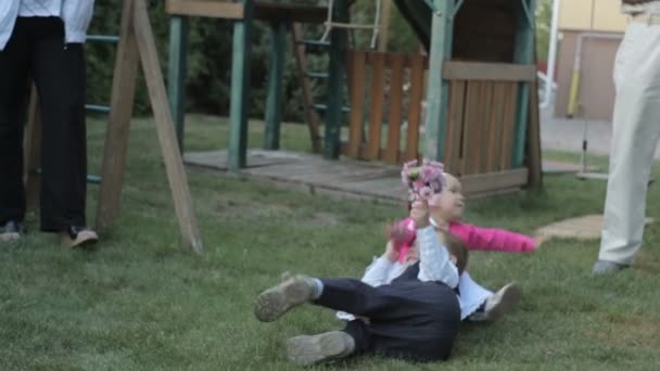 Маленький мальчик и маленькая девочка на зеленой траве играть — стоковое видео