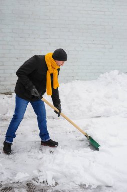 adam bir turuncu Fularlı kar temizler