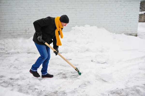 Mann mit orangefarbenem Schal reinigt Schnee — Stockfoto
