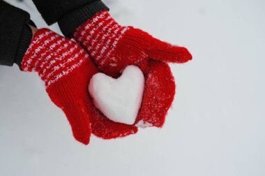 Kırmızı mittens karlı bir kalp tutan kadın