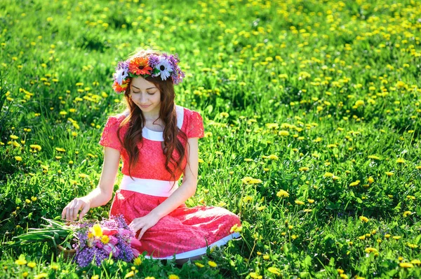 Jeune femme en robe rouge allongée sur l'herbe dans la prairie — Photo