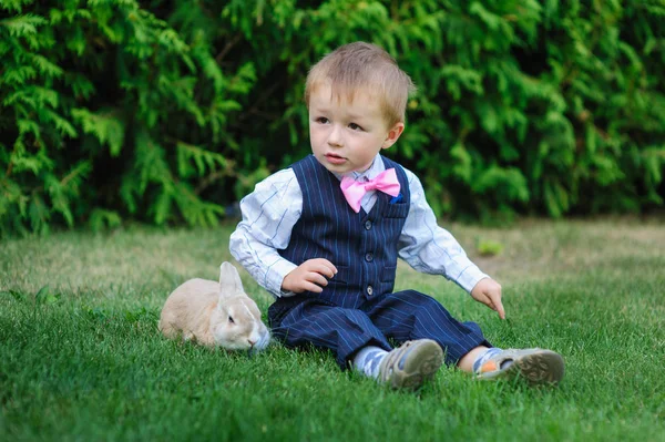 Mały chłopiec siedzi na trawie z Krolik — Zdjęcie stockowe