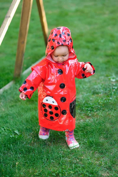 Kleines Mädchen in rotem Mantel läuft auf dem Gras — Stockfoto