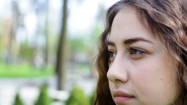 Jovem mulher olhando para longe em um parque de verão. Face close-up — Vídeo de Stock