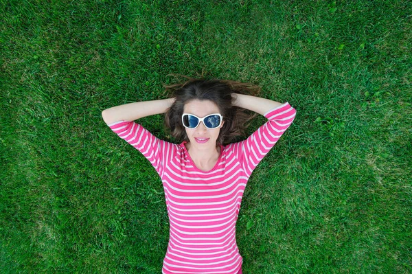 Parktaki çimlerin üzerinde uzanan güzel genç bir kadın.