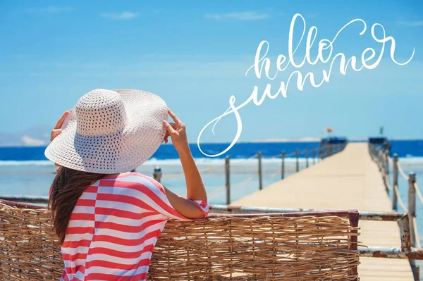 Achteraanzicht van de close-up van vrouw in witte hoed uitkijken naar blauwe oceaan en hemel en woorden Hello zomer. Kalligrafie, belettering — Stockfoto