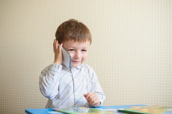 Μικρό αγόρι κάθεται στο γραφείο και να μιλάμε στο τηλέφωνο — Φωτογραφία Αρχείου