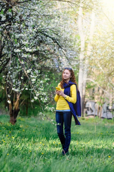 Bela jovem mulher andando no exuberante jardim de primavera — Fotografia de Stock