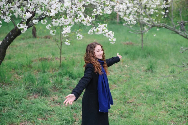 Schöne glückliche junge Frau, die in einem blühenden Frühlingsgarten spaziert — Stockfoto