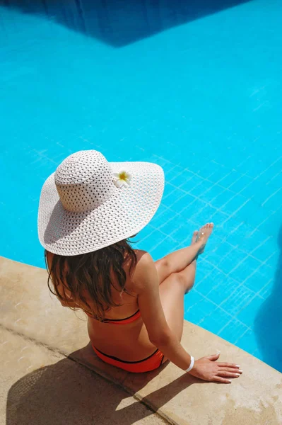 Schöne junge Frau im Resort sitzt am Rande des Pools — Stockfoto