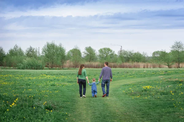 Joven familia y joven hijo caminar en un prado de primavera — Foto de Stock