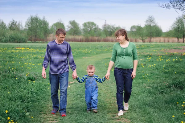 Joven familia y joven hijo caminar en un prado de primavera — Foto de Stock