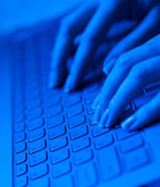 Laptop klavye mavi tonlarda parmaklar kadın