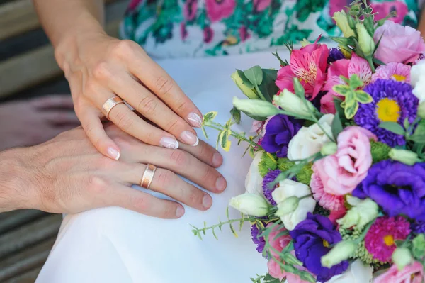 Руки нареченого і нареченого з кільцями і весільним букетом — стокове фото