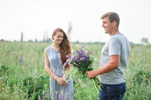 Homme donne une femme un bouquet de fleurs sauvages sur une promenade — Photo