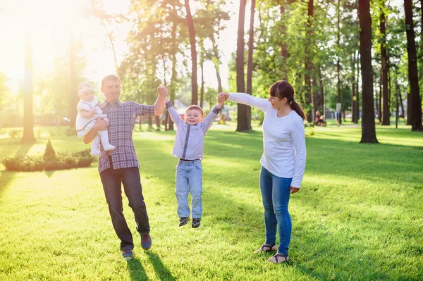 Jonge ouders met kinderen lopen in het park van de zomer — Stockfoto