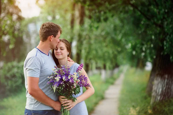 Jovem casal apaixonado por um buquê de flores em um fundo do caminho — Fotografia de Stock