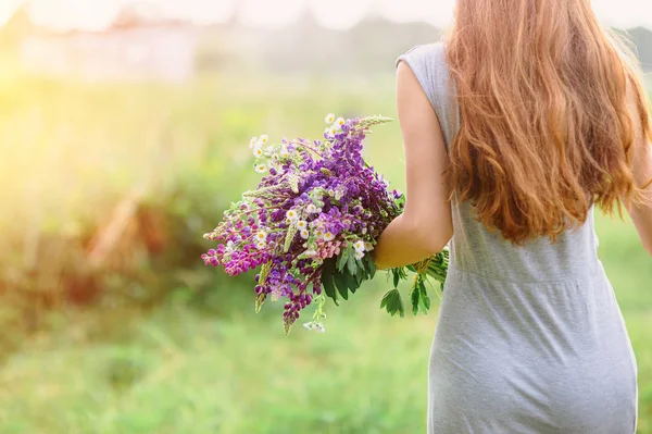 Mulher com um buquê de flores de tremoço em um dia ensolarado de verão — Fotografia de Stock