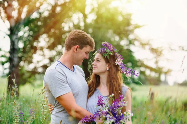 Belo jovem casal no jardim da primavera com um buquê de flores silvestres — Fotografia de Stock