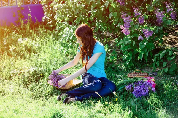 Young woman sitting in the park on the grass with flowers — Stock Photo, Image