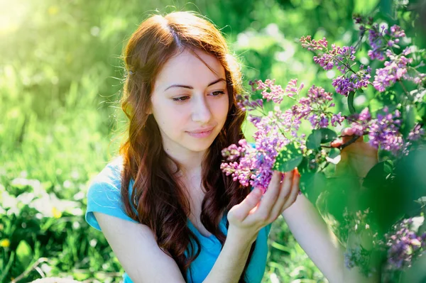 Jovem mulher perto do arbusto lilás no parque da primavera — Fotografia de Stock