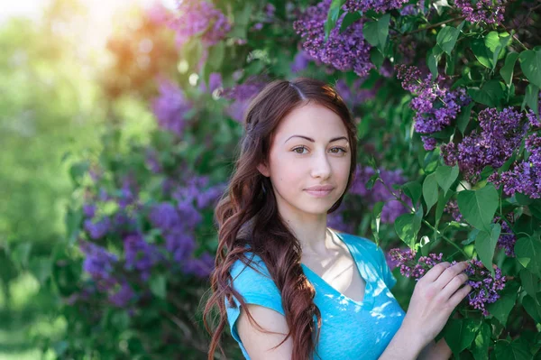 Young woman near the lilac bush in the spring park — Stock Photo, Image