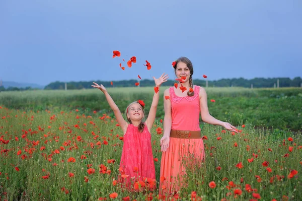 Две девушки в красном платье ходят по маковому полю весной — стоковое фото