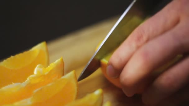 Mann schneidet die Orange auf einem Holzbrett — Stockvideo