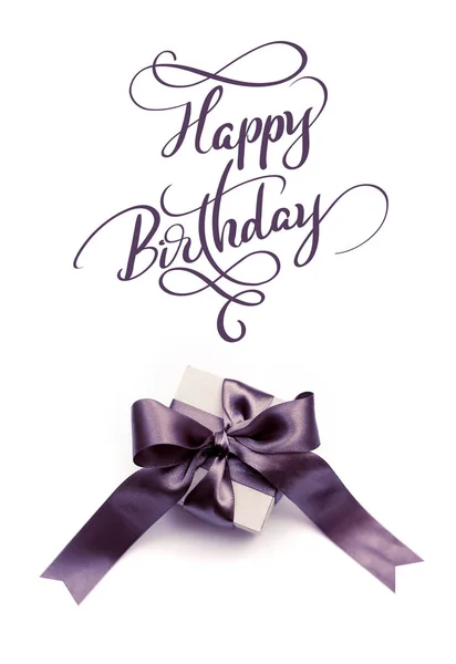 Caja de regalo con lazo marrón sobre fondo blanco y texto Feliz cumpleaños. Letras de caligrafía —  Fotos de Stock