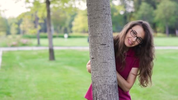 Hermosa mujer feliz en un parque cerca de un árbol — Vídeos de Stock