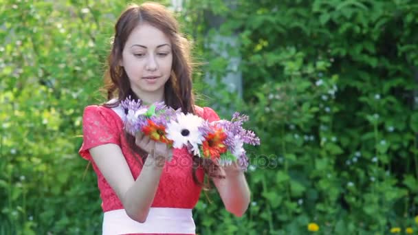 Vacker ung kvinna i en spring park med en krans av blommor — Stockvideo