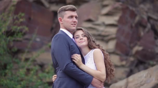 Novia y novio abrazar en un paseo de bodas en el fondo de la montaña — Vídeo de stock