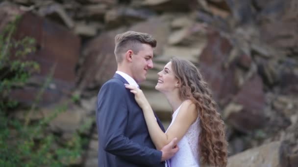 Braut und Bräutigam umarmen sich auf einem Hochzeitsspaziergang im Hintergrund des Berges — Stockvideo
