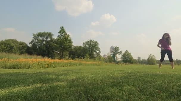 美しい若い女性は、夏の草原を歩いています。 — ストック動画