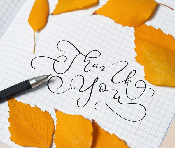 Yellow leaves and a pen on a piece of paper and text Thank you. Calligraphy lettering hand draw — Stock Photo, Image
