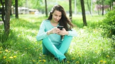 Mutlu kadın çiçek açan, çimlerin üzerine oturan telefon ile bahar bahçe