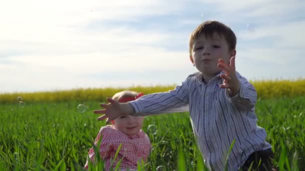 Menino e menina pegar bolhas de sabão — Vídeo de Stock