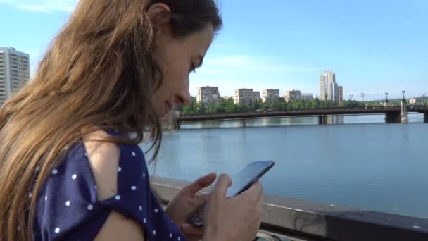 Belle femme avec un smartphone près de la rivière 