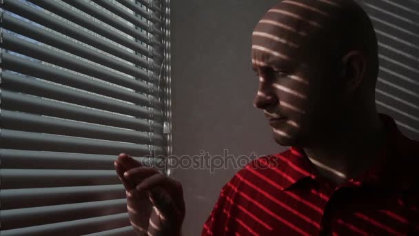 Young man in the office looks through the blinds — Stock Video