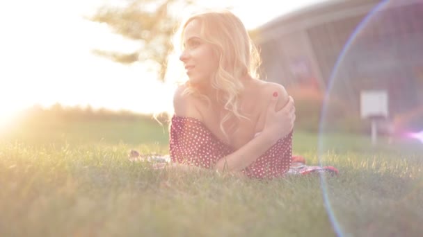 Jonge mooie vrouw ligt op het gras in het park — Stockvideo