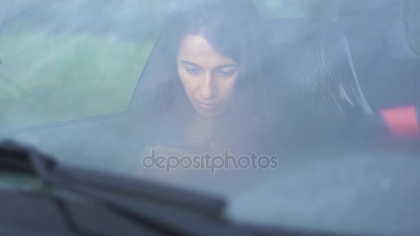Schöne junge Frau sitzt mit Smartphone im Auto — Stockvideo