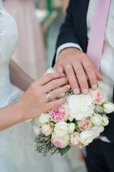 Ręce z pierścieniami na tle Bukiet ślubny — Zdjęcie stockowe