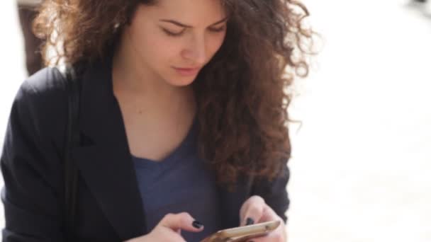 Beautiful young woman with a smartphone in the hands of the city — Stock Video