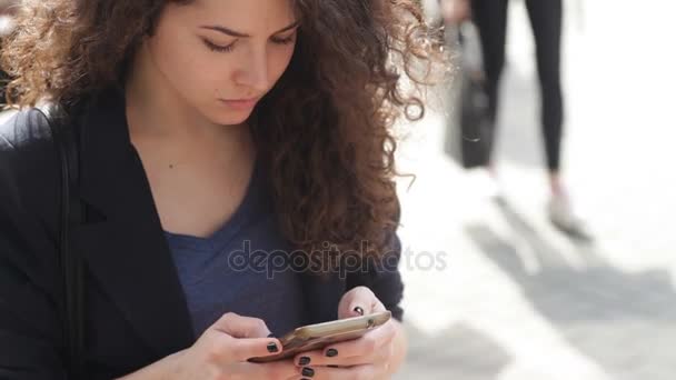 Hermosa joven con un teléfono inteligente en las manos de la ciudad — Vídeo de stock