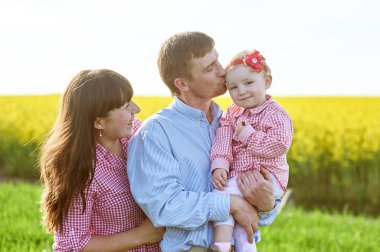 Anne ve baba ve kızı yaz yeşil sahada yürüyor