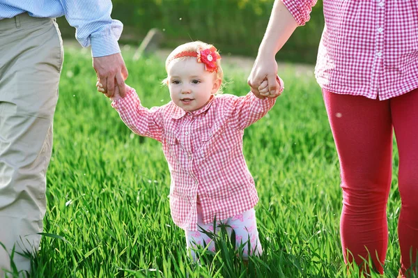 Mamá y papá y su hija están caminando en el campo verde de verano —  Fotos de Stock